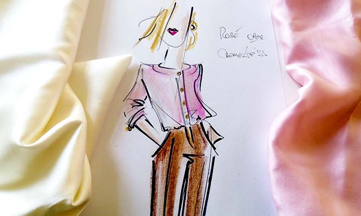 Illustrierte Modeskizze mit einer Dame in einer rosanen Seidenbluse und einer braunen Hose, rechts und links echte Seidenstoffe